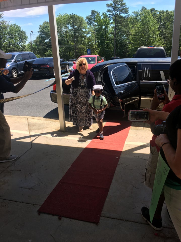 As the kids step out of the limo onto the red carpet, their teacher announces each "millionaire."