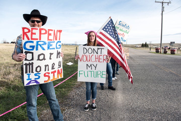 Protestors hold signs at an April rally for Republican Greg Gianforte.