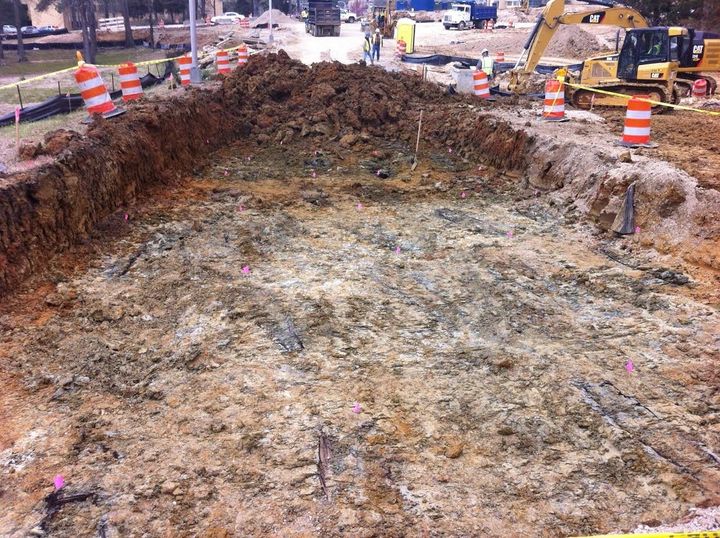 Outlines of wooden coffins found during excavations at the University of Mississippi Medical Center’s campus are seen. Each grave is marked with a pink flag.