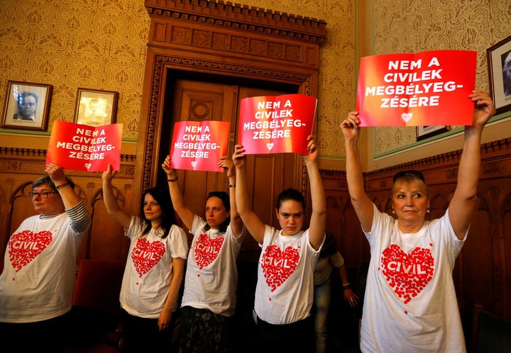 Protestors hold banners saying ‘No to the stigmatisation of civilians’ at a meeting of the Hungarian parliament’s justice com