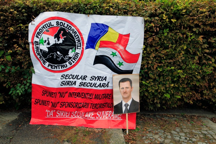 A portrait of Syrian President Bashar Assad is seen next to a banner of the European Front of Solidarity for Syria during a demonstration by members of the Syrian community in Bucharest in 2013.