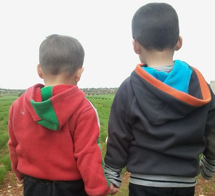 Mohammed's two twin boys walk outside near their home in Idlib.