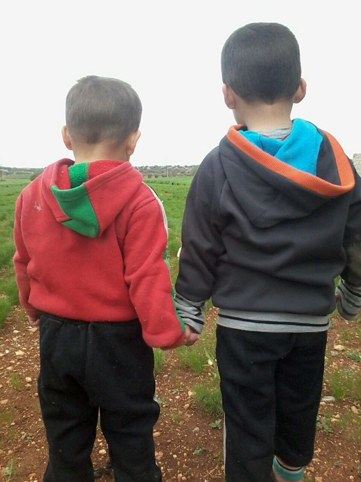 Mohammed's two twin boys walk outside near their home in Idlib.