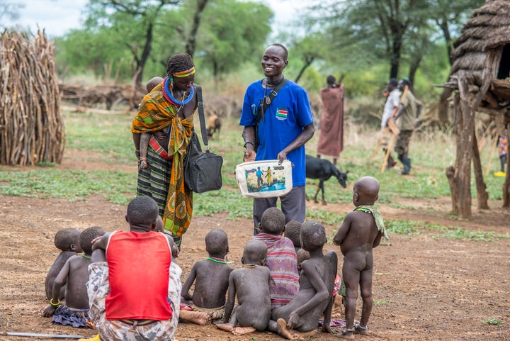 A health worker in South Sudan uses a picture book to teach children and adults how to avoid contracting Guinea worm disease.