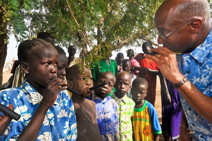 The Carter Center's Dr. Donald Hopkins shows South Sudanese children how to use plastic water filtration pipes.