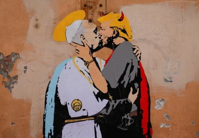 A mural signed by 'TV Boy' and depicting Pope Francis and U.S. President Donald Trump kissing, is seen on a wall in downtown