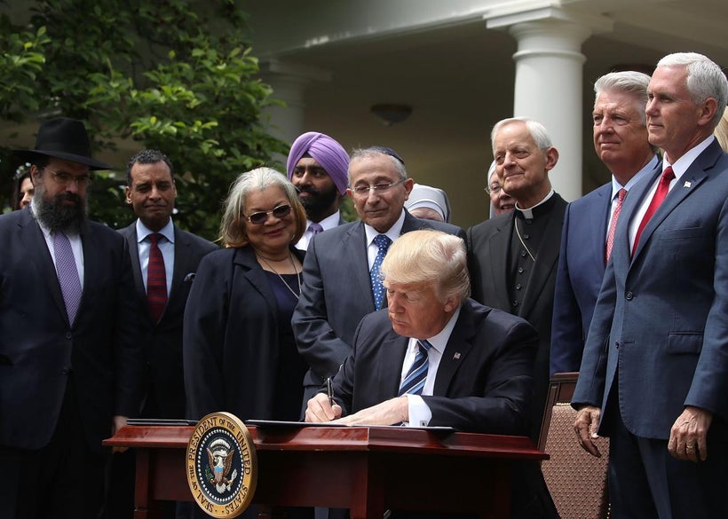 Donald Trump is flanked by clergy members as he signs an Executive Order during a National Day of Prayer event on May 4, 2017
