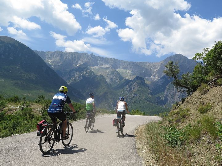 <p><em>BikeTours.com President Jim Johnson (left) and Cycle Albania guide Junid (middle) riding e-bikes on the mountain roads of Albania.</em></p>