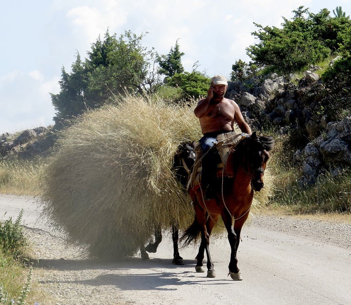 <p><em>Biking gives you the flexibility to stop and take in a scene, like this fellow on his cell phone as he travels on his hay cart.</em></p>