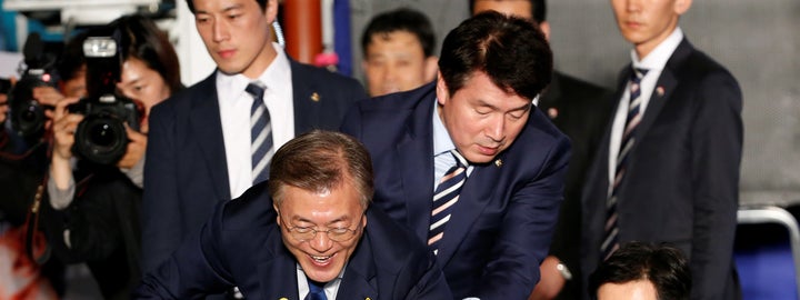 President Moon Jae-in reaches to the crowd as his now-famous bodyguard in the background looks as handsome as ever.