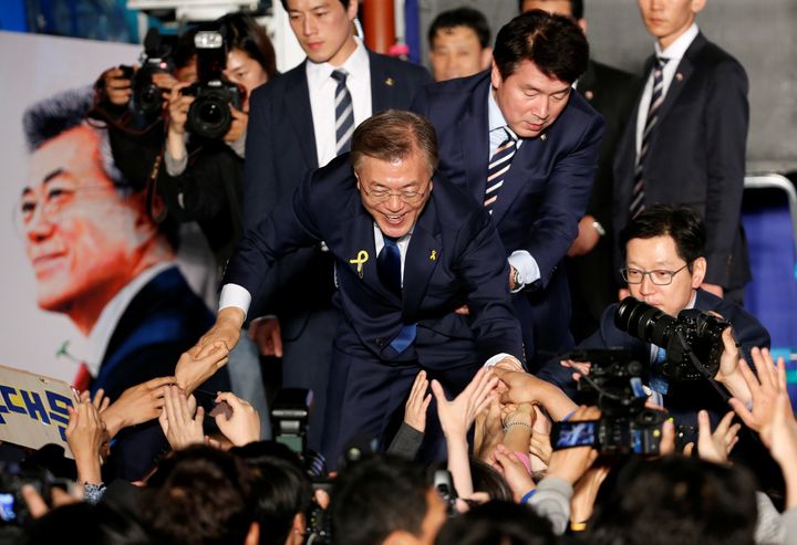 President Moon Jae-in reaches to the crowd as his now-famous bodyguard in the background looks as handsome as ever.