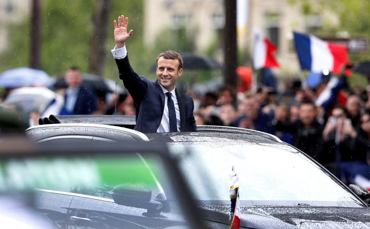 French President Emmanuel Macron waves from his car on the Champs Elysees avenue after the handover ceremony in Paris, France.
