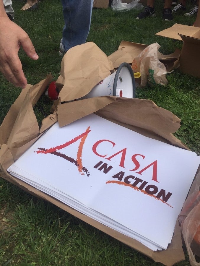 <p><em>Protesters reach for signs at May Day protests. Photo by Aya Elamroussi </em></p>