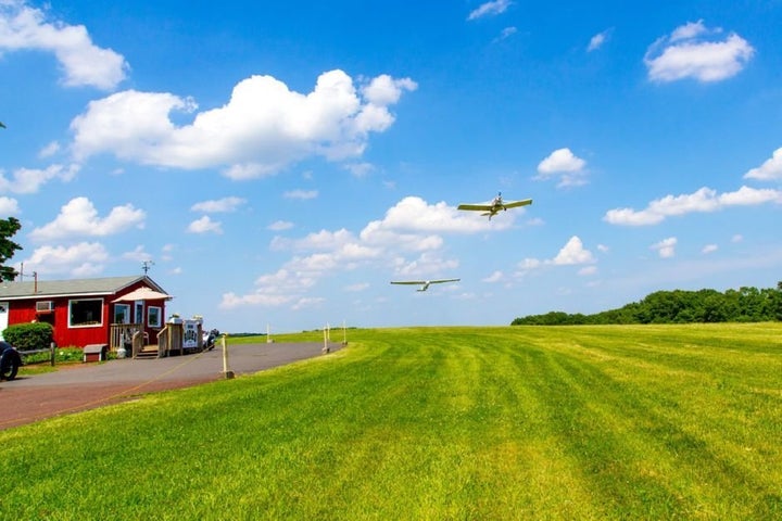 A towplane pulls a glider aloft on the grass airstrip at Van Sant Airport in Bucks County, Pennsylvania. The little airport's