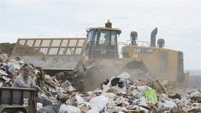 Gulls fly overhead as a compactor manages the flow of garbage at a Colorado landfill. States are trying to reduce the amount of food that ends up in landfills.