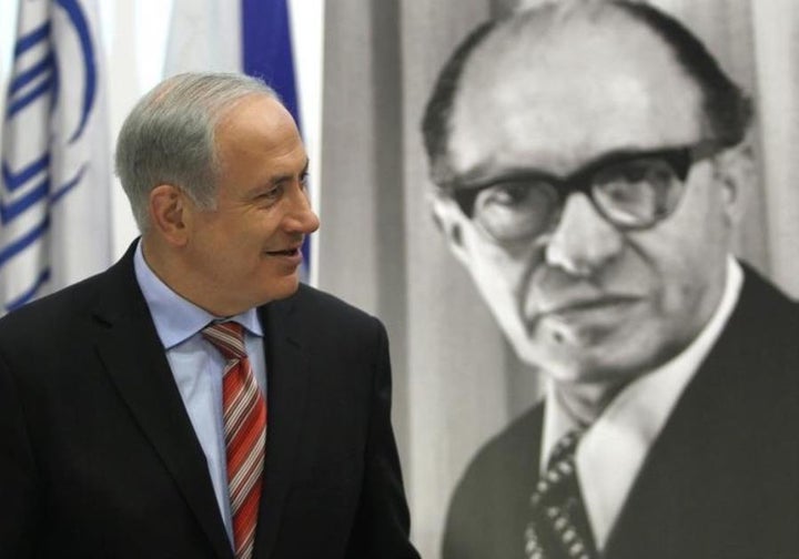 Prime Minister Benjamin Netanyahu walks in front of a poster of the late Prime Minister Menachem Begin upon his arrival at the Likud party meeting at the Menachem Begin Heritage Center in Jerusalem.