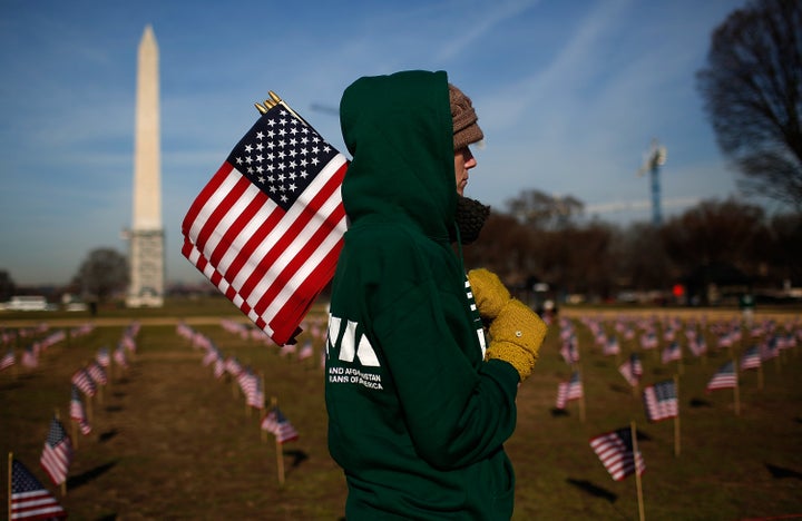 Iraq war veteran Sara Poquette helps set up 1,892 American flags on the National Mall March 27, 2014 in Washington, DC. The Iraq and Afghanistan Veterans of America installed the flags to represent the 1,892 veterans and service members who committed suicide this year as part of the 'We've Got Your Back: IAVA's Campaign to Combat Suicide.' (Photo by Win McNamee/Getty Images)