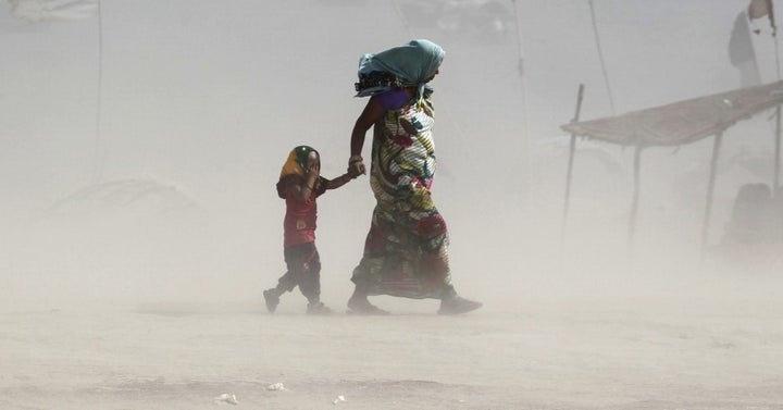 A mother and her child walk along the Ganges river during a dust storm on a hot summer day in Allahabad, India, June 9, 2015.