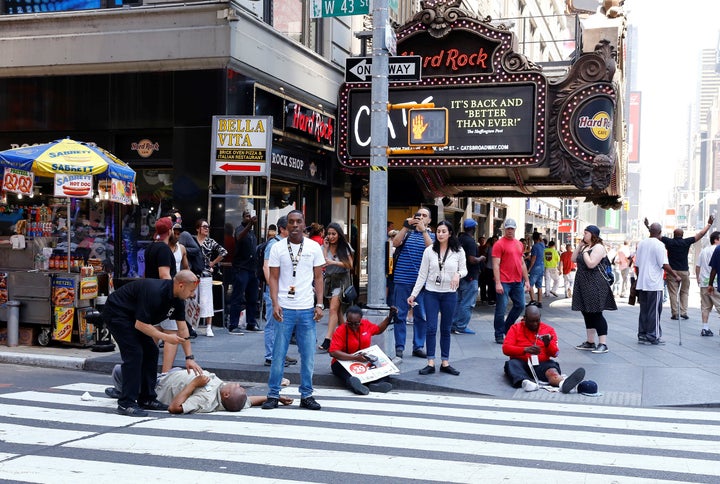 Wounded civilians receive first aid on the ground after a maroon sedan vehicle crashed into pedestrians