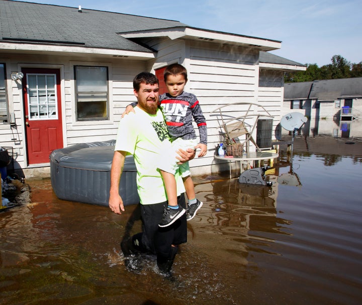 A man carries his son through flood waters surrounding their Greenville, North Carolina, home on Oct. 14, 2016, in the aftermath of Hurricane Matthew.