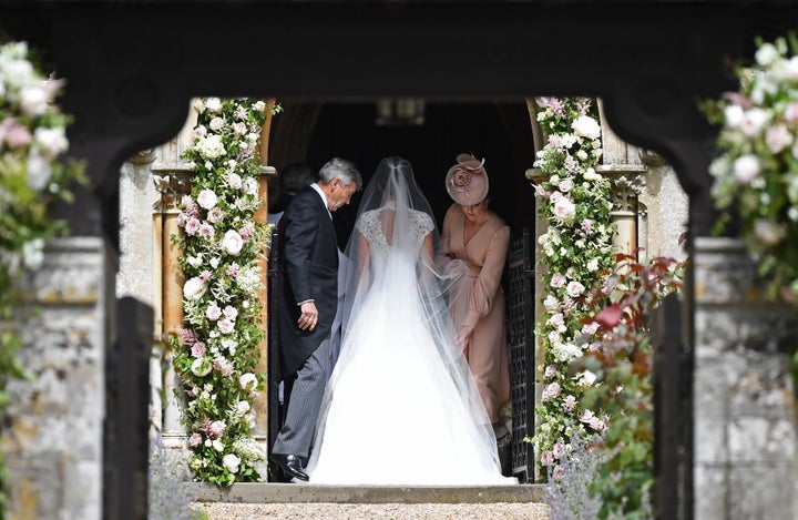 Duchess Kate, in a pale pink dress, adjusted Pippa's gown. 