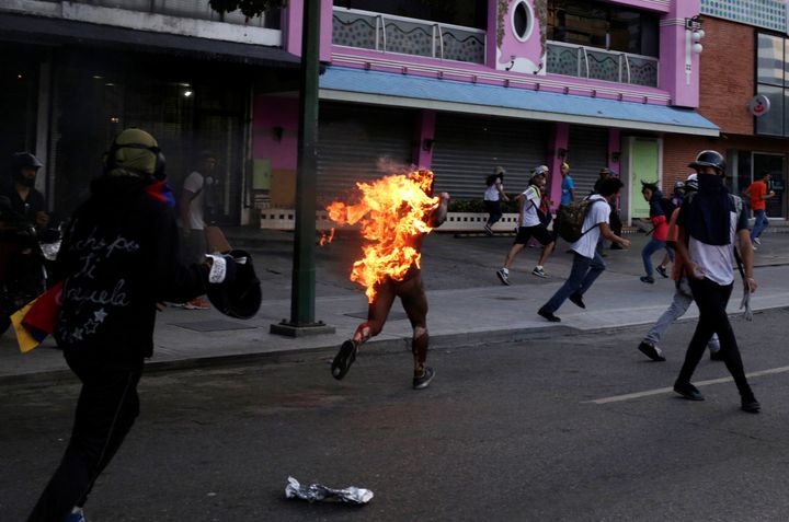 A man who was set on fire by people accusing him of stealing during a rally against Venezuela's President Nicolas Maduro runs amidst opposition supporters in Caracas, Venezuela, May 20, 2017.