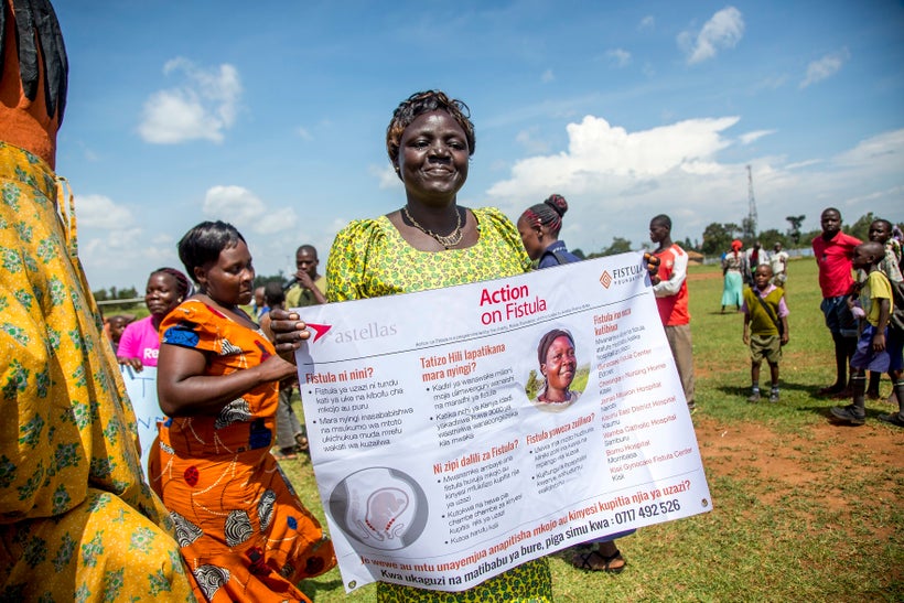 An outreach worker holds a sign about fistula at an Action on Fistula.