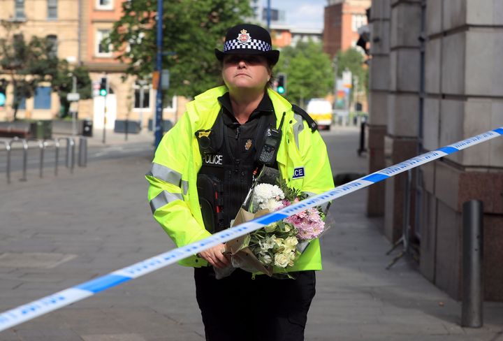 A police officer moves a floral tribute close to the Manchester Arena