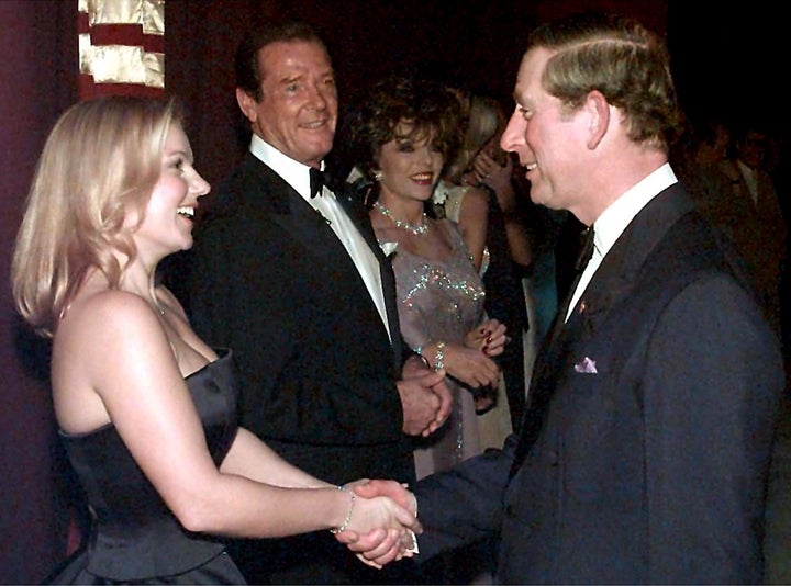 Prince Charles and Geri "Ginger Spice" Halliwell shake hands as Roger Moore and Joan Collins look on.