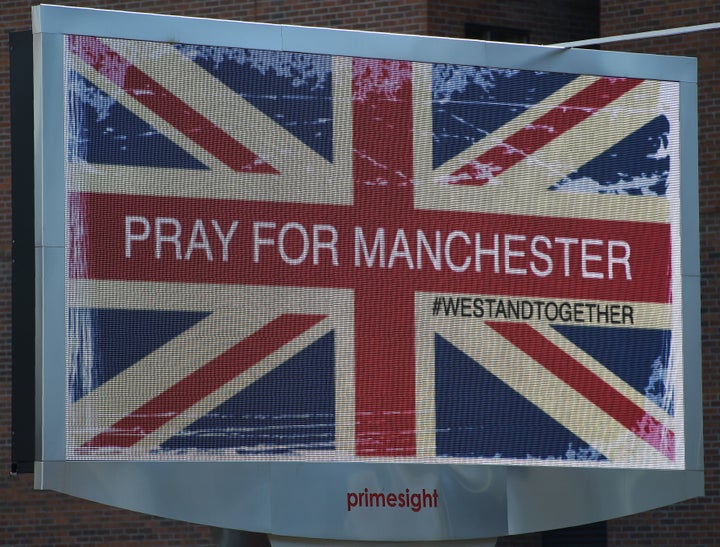 An electronic advertising board displays a Union flag and the words "Pray for Manchester," close to the Manchester Arena.