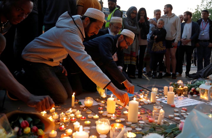 Men light candles following a vigil in central Manchester on Tuesday