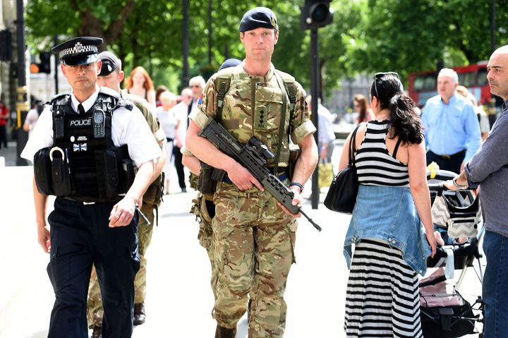A member of the army joins police officers on Whitehall, London, after Scotland Yard announced armed troops will be deployed to guard "key locations" such as Buckingham Palace, Downing Street, the Palace of Westminster and embassies