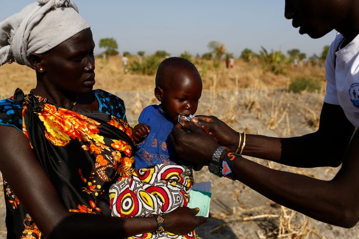 Angelina Nyanin, 25, holds her niece, Nyalel Gatcauk, two, who suffers from malnutrition, as a UNICEF nutrition worker feeds the baby Plumpy'Nut, a peanut-based paste for treatment of severe acute malnutrition during a Rapid Response Mechanism mission in Thonyor, Leer county, South Sudan, 26 February 2017.