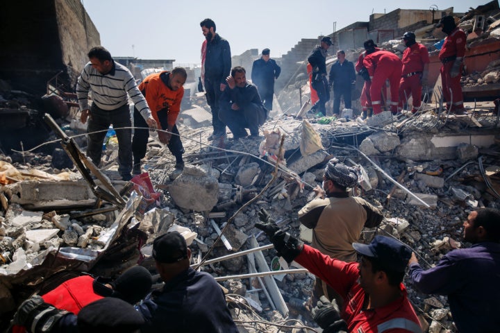 Local residents help Iraqi civil defense force members recover corpses trapped in the rubble of a home destroyed by reported