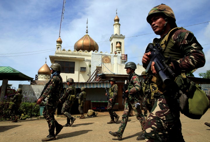 Government troops walk past a mosque before their assault with insurgents.