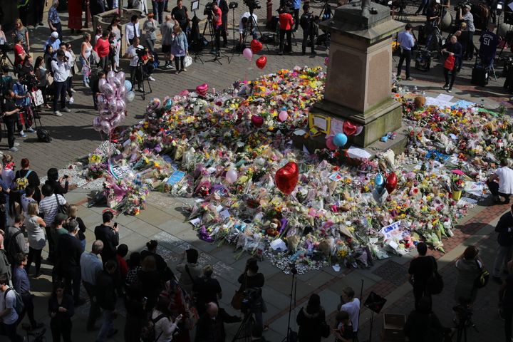 People gather around floral tributes to the victims of the Manchester attack at St Ann's Square on Wednesday
