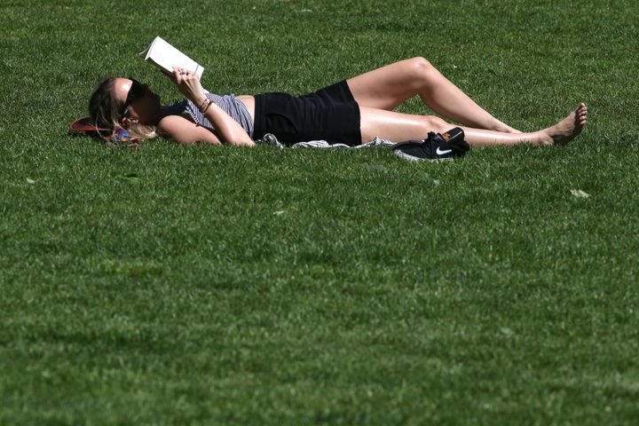 A woman enjoys a book in the blistering heat which swept across England on Friday