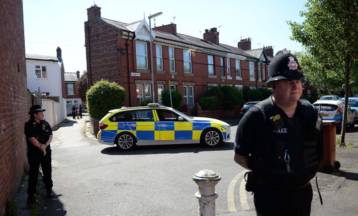 Police stand guard outside a property on Dorset Avenue in Moss Side, Manchester on Friday