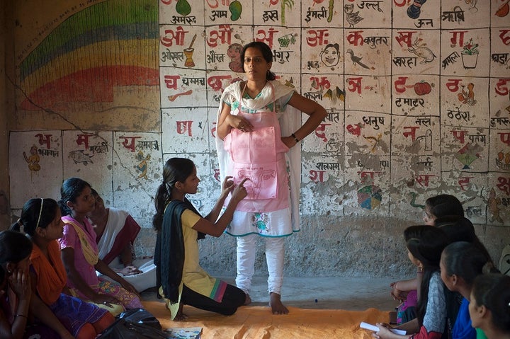 Kushboo Kumari (C sitting) ,15, gestures as she explains a diagram made on an apron worn by Manita (L),15, during an interactive session with her peers on menstrual health in a village in Bihar, India. 