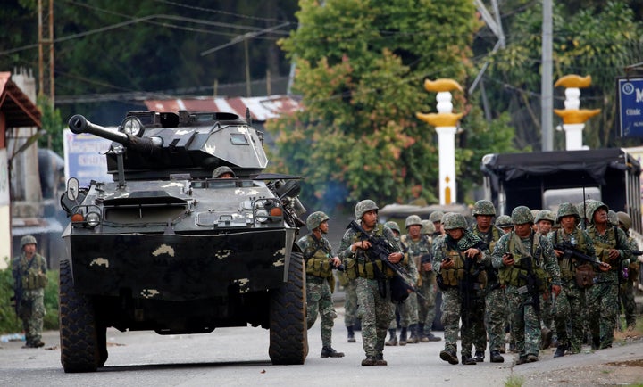 Members of Philippine Marines walk next to an armoured fighting vehicle (AFV) as they advance their position in Marawi City,