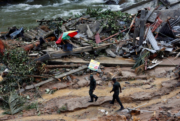The rains caused both heavy flooding and enormous landslides. In this photo, Sri Lankan army soldiers walk past the debris of