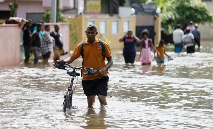 More than 150 people have lost their lives in the disaster. This photo shows a man pushing his bike through a flooded road in Dodangoda village in Kalutara. 