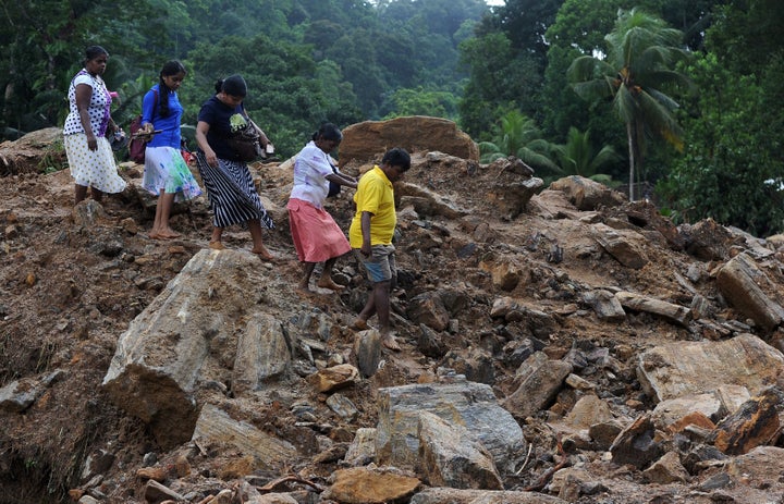 Sri Lankan villagers cross a landslide site in Kalutara. 