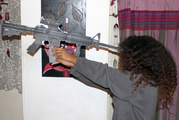 <p>Toveet’s sister holds a mock-up of the same rifle issued to Toveet, demonstrating that Toveet could not have reached the rifle trigger or have killed herself in the way that the Israeli army claims that she did</p>