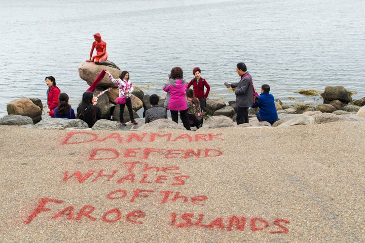 People take photos near the Little Mermaid statue, which was painted red in what local authorities say is an act of vandalism in Copenhagen on May 30, 2017.