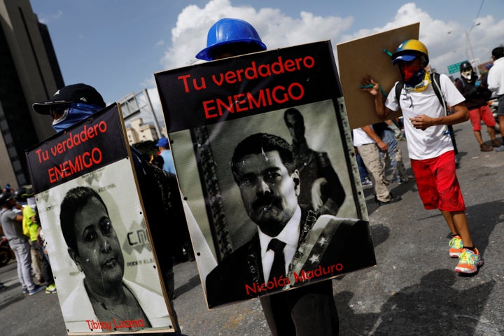 Demonstrators carry signs of Maduro and National Electoral Council President Tibisay Lucena that reads " your real enemy." Caracas, May 27.