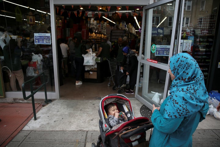 A Muslim American woman wearing hijab awaits outside the Balady halal supermarket with a child ahead of the first day of Ramadan in Brooklyn, New York, U.S. on May 26, 2017.