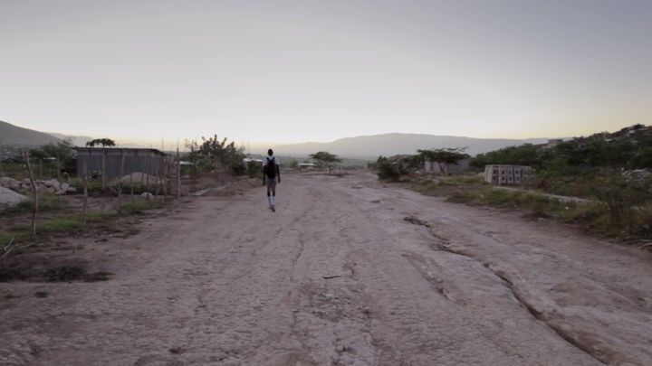 Pierre Joseph walking on the outskirts of Port-Au-Prince, Haiti to the basketball court