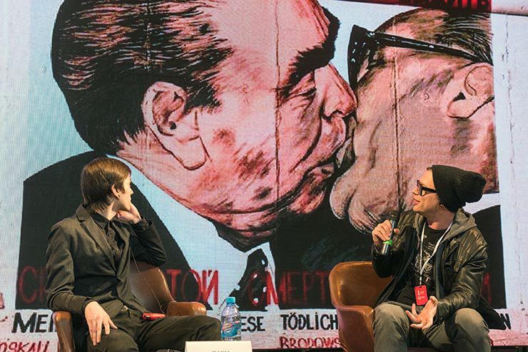 Artist Pasha Kas and the UN’s Denis Leo Hegic discussing My God, Help Me to Survive This Deadly Love sometimes referred to as the Fraternal Kiss (German: Bruderkuss), a graffiti painting on the Berlin Wall by Dmitri Vrubel, 1990. The painting depicts Leonid Brezhnev and Erich Honecker. Street Art Museum. Saint Petersburg, Russia. May 2017. (photo © Martha Cooper)