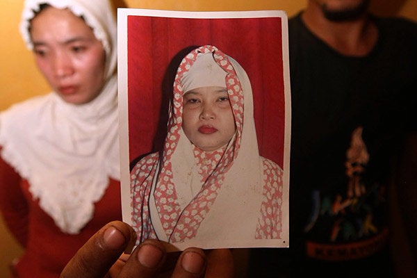 Irwan Setiawan along with his sister Evi Kurniati holds a picture of his mother Ruyati Binti Sapubi in their house in Bekasi
